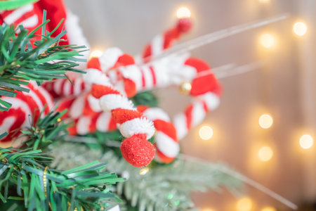 Candy cane ornament hanging on a Christmas tree Christmas tree against a bokeh background of holiday...