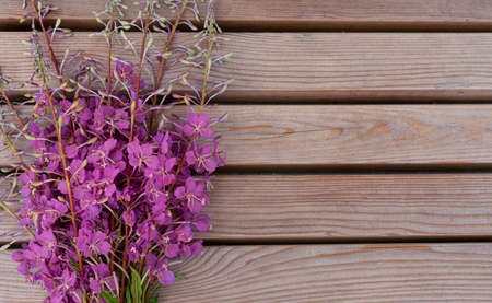 Bouquet of bright pink wildflowers, rosebay willow-herb, on a wooden textured surface.