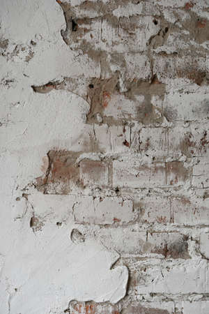 old brick wall painted with white paint and partially plasteredの写真素材