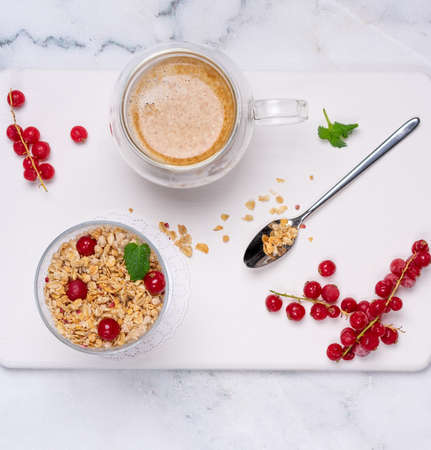 bright breakfast, a cup of coffee and cereal with red currant berries on a white background from above. Concept of a beautiful healthy breakfastの写真素材