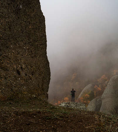 landscape mountains in autumn trees and fog with a little manの写真素材