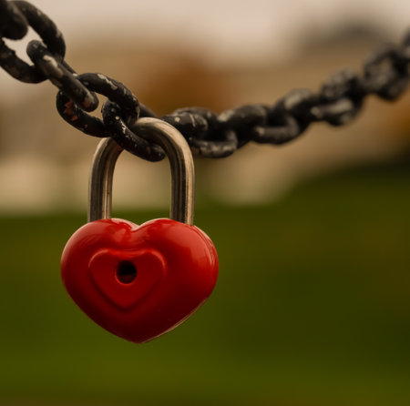 a red heart-shaped padlock hangs on a chain, a symbol of love and loyalty