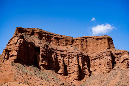 Bright orange mountains against the blue sky with cloudsの写真素材