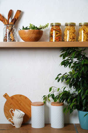 jars of pasta and wooden dishes on a wooden table and on a shelf in the kitchen