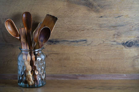spoons and other wooden utensils in a jar on a wooden tableの写真素材