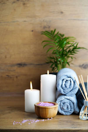 spa and aromatherapy concept-candles, towels, pink sea salt and an aromatic reed diffuser on a wooden tableの写真素材