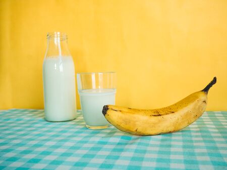 Pouring milk into glass with banana on yellow backgroundのeditorial素材