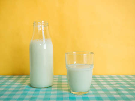 Pouring milk into glass on yellow backgroundのeditorial素材