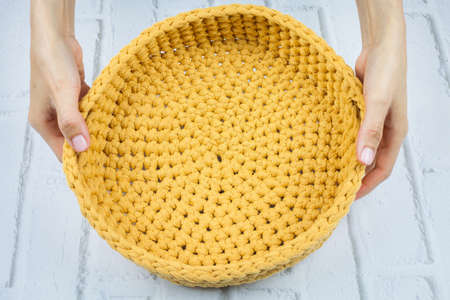 Crochet basket made of yellow thread. Wicker basket made of yellow fabric. Image on white background.の写真素材