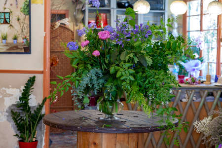 flower arrangement with purple and pinl flowers, green leaves and eucalyptus on wooden tableの写真素材