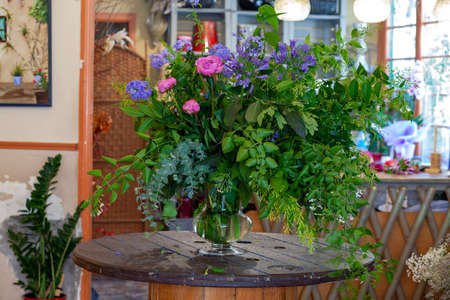 flower arrangement with purple and pinl flowers, green leaves and eucalyptus on wooden tableの写真素材