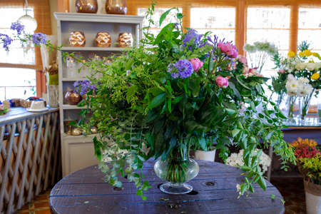 flower arrangement with purple and pinl flowers, green leaves and eucalyptus on wooden tableの写真素材