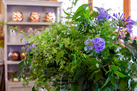 flower arrangement with purple flowers, green leaves and eucalyptus on wooden tableの写真素材