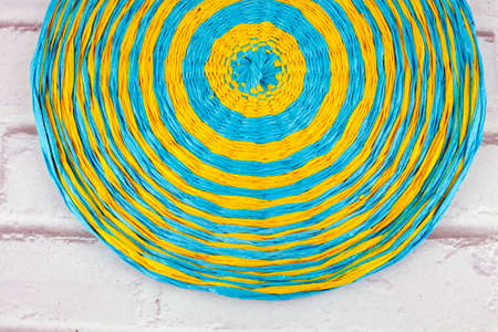 Colorful round handmade placemat of blue and yellow paper thread on white background.の写真素材