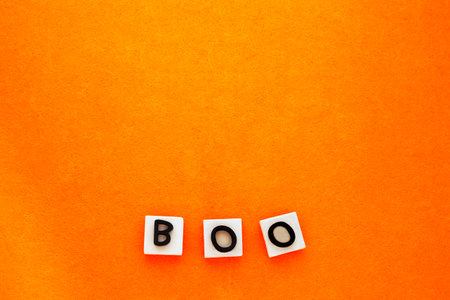 Minimalistic boo scary concept. Boo word phrase on orange background. Copy space, place for text. Flat lay top view. Minimal halloween backgroundの写真素材