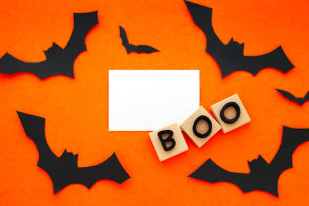 Boo word phrase and black bats on orange background. Crafts of the concept of Halloween. Bats, cut out of paper Copy space, place for text. Flat lay top view. Minimal Halloween background.の写真素材