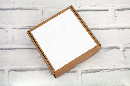 Cardboard box with space for text on white brick background. Label on the surface for copy space. Closed box. Top view.の写真素材