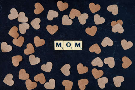 Mother's day concept. Letters of the alphabet in the form of the word MOM with hearts on a black background. Top view, close-upの写真素材