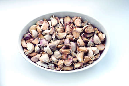 Large quantity of garlic cloves inside oval container on white background. top viewの写真素材