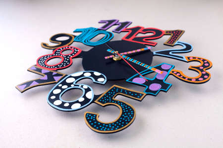 Colorful round clock made of wood with big and funny numbers. The subject of interior in your home. Clock on a white background.の写真素材