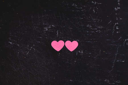 Two pink hearts on dark textured slate background. Love, Mother's day and wedding concept. Flat lay top view. Minimal Valentine's background.の写真素材