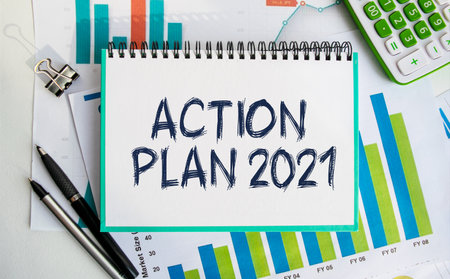Notepad with the inscription ACTION PLAN 2021. Conceptual image, business accessories, calculator isolated on the desktop. Finance or business concept.の写真素材