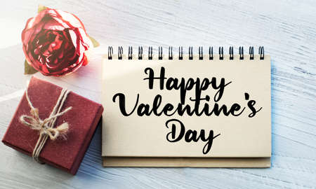 Notepad with writing on a light table along with a flower and a vintage gift box. Natural light. Festive concept. The inscription is associated with Valentine's Day, Mother's Day or Women's Day.の写真素材