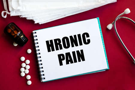 The inscription on a notebook on a medical theme. Doctor's workplace. Top view on a red background with medical equipment - stethoscope, medical masks, glasses.の写真素材