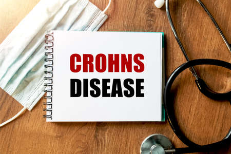 Inscription - CROHNS. Written in a notepad to remind you of what's important. Top view of the table...