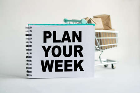 Notepad with the inscription PLAN YOUR WEEK. Conceptual image, business accessories, calculator isolated on the desktop. Finance or business concept.の写真素材
