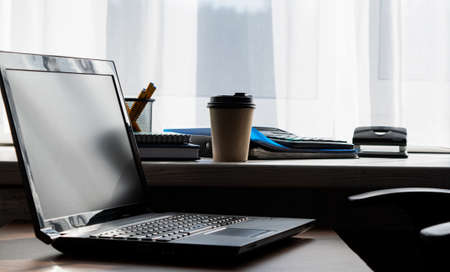Laptop on the table. window in the background. work from home. office equipment in the workplace. Conceptual image of office work.の写真素材