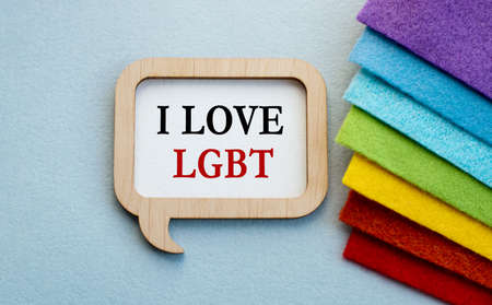 An open envelope with the words I LOVE LGBT rests on a stack of fabric folded in the colors of the...