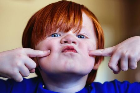 4 year old boy pushing fingers into faceの写真素材