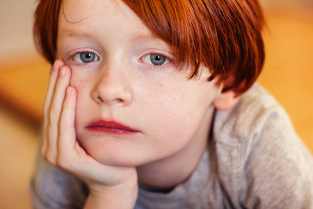 7 year old boy resting head in hand