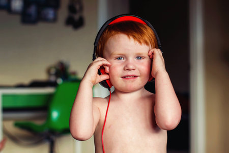 two year old redhead boy playing with headphonesの写真素材