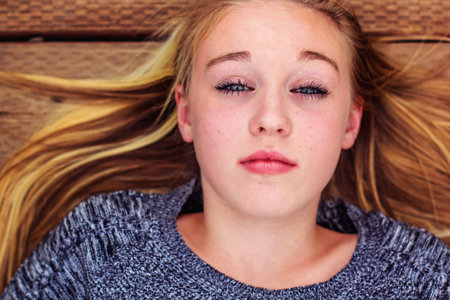 tween girl laying down on a bridge in the park