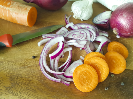 onions carrot garlic knife on a wooden boardの写真素材