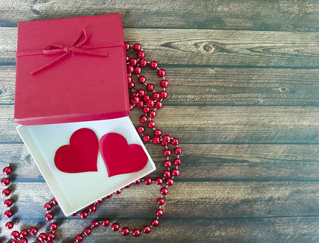two red hearts on a wooden background, red box, romantic, beadsの写真素材
