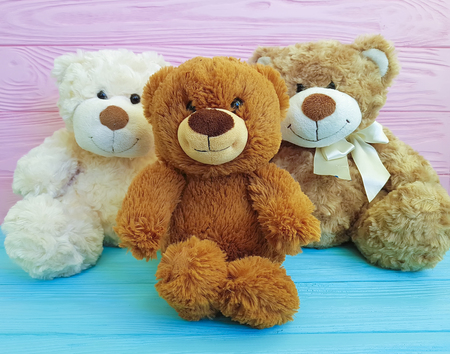 cute three teddy bear toy with on colored wooden,の写真素材