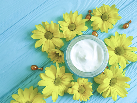 cosmetic cream yellow flowers camomile capsules on a blue wooden backgroundの写真素材