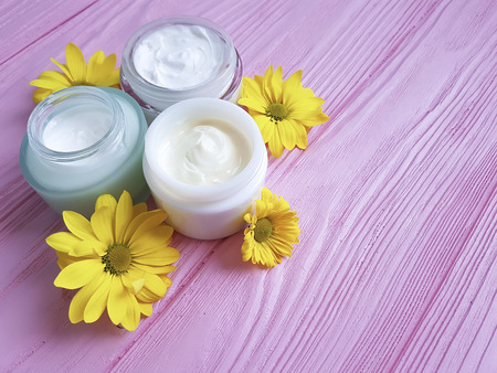 cream cosmetic yellow flowers pink wood background