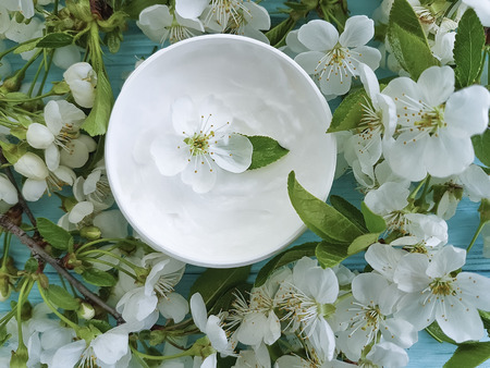 cream cosmetic blossoming cherry on a blue wooden backgroundの写真素材