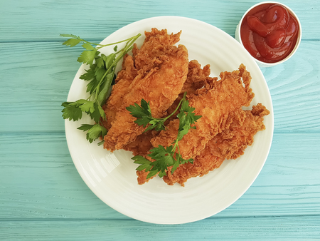 fried chicken in breading, parsley, ketchup on blue woodenの写真素材