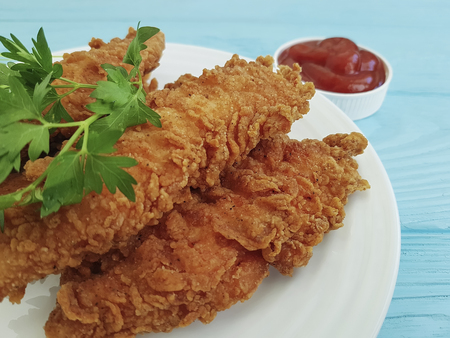 fried chicken in breading, parsley, ketchup on blue woodenの写真素材