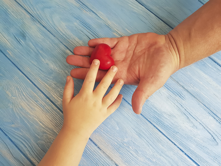 Father's Day Hands Dad and Child's Heart on a Blue Wooden Backgroundの写真素材