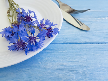 flowers cornflowers, plate, fork knife on a wooden backgroundの写真素材