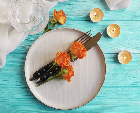 rose, fork, plate and knife on wooden tableの写真素材