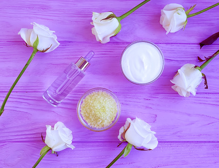 cosmetic cream, rose flower, salt on a wooden background