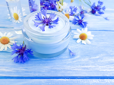 cosmetic cream, chamomile flower, cornflower on a wooden backgroundの写真素材