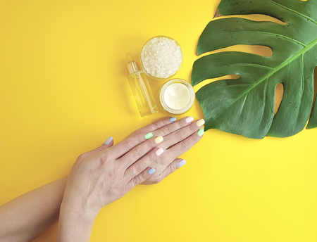 female hands, cosmetic cream, monstera leaf, on a backgroundの写真素材